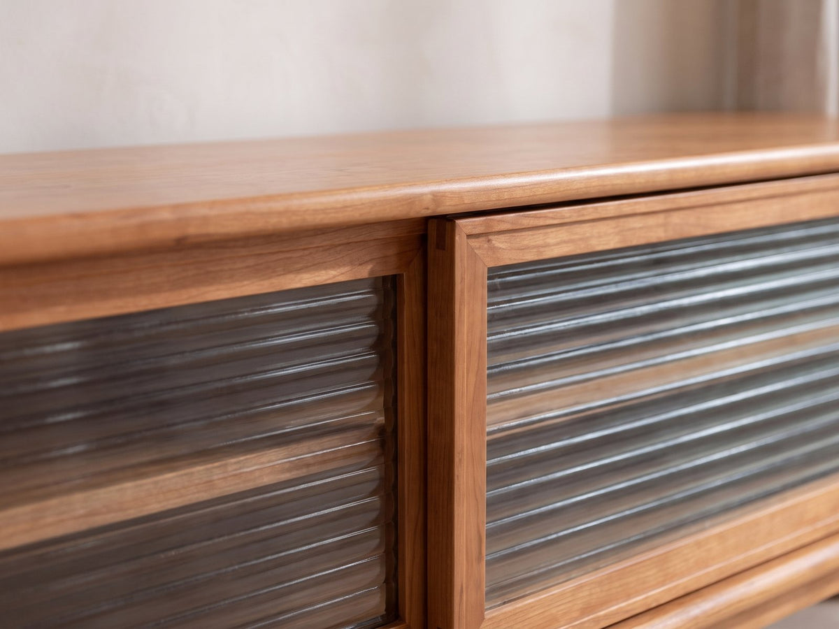 Close-up of the Cividale Solid Cherry Media Console: the two sliding reeded-glass doors and their solid cherry frames