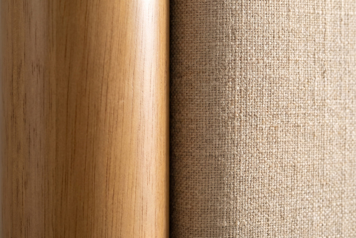 Close-up of the Civitella bed where a light walnut rubberwood post meets the beige woven headboard fabric