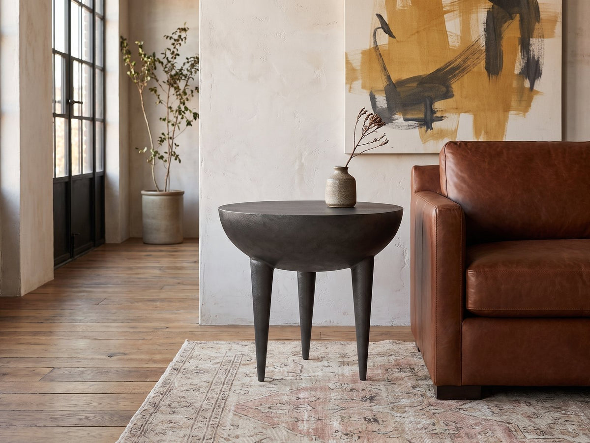 Colledara Cast Aluminum Bowl Side Table beside a leather sofa in an industrial loft