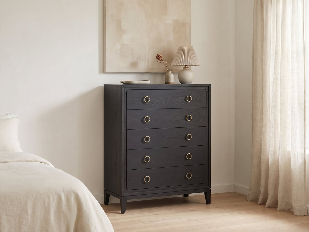 Cologna 40-Inch Peppercorn 5-Drawer Chest against a plaster wall under an abstract canvas in a bright bedroom
