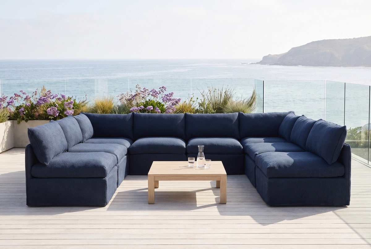 Comiso navy U-shaped outdoor sectional on a whitewashed deck above the ocean in Laguna Beach, California, behind a glass balustrade (coffee table not included)