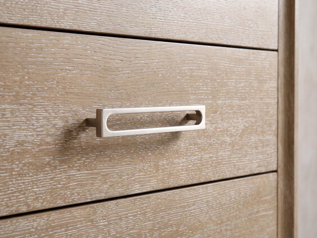 Close-up of the Cortina 40-Inch Natural Oak 5-Drawer Chest: the satin-nickel open-loop bar pull on a wire-brushed oak drawer