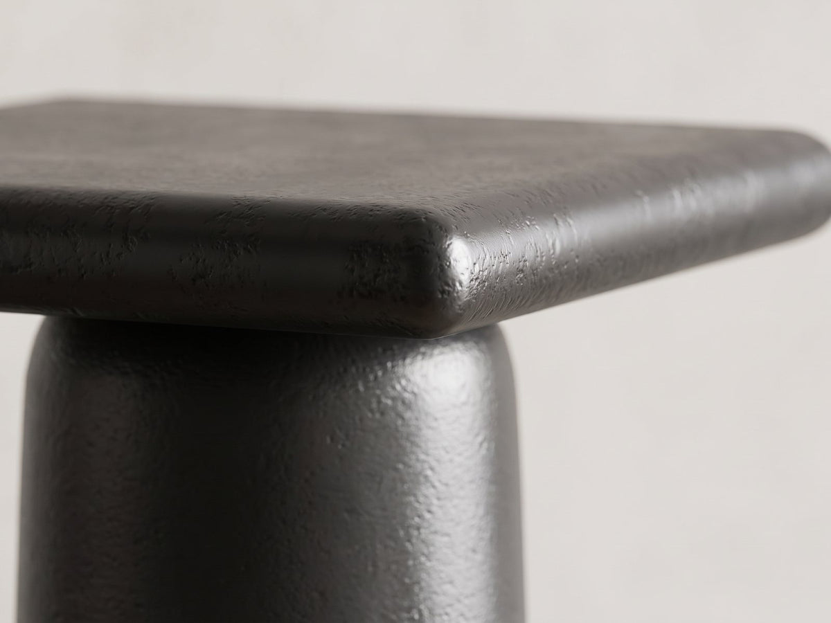 Close-up of the Cortona Cast Aluminum Pedestal Coffee Tables, Set of 2: the rounded top edge meeting the round cast aluminum column