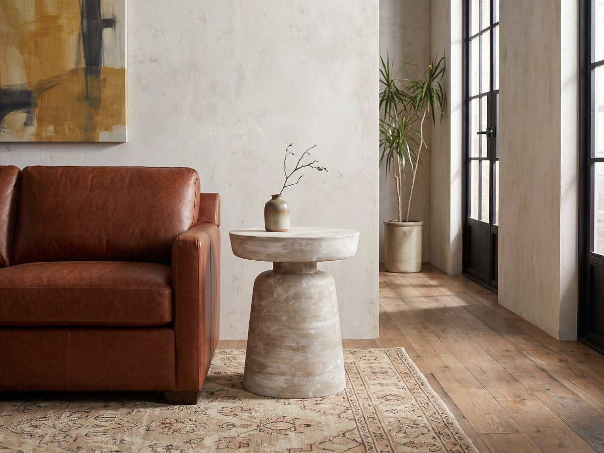 Craco Whitewashed Mango Pedestal Side Table beside a leather sofa in an industrial loft