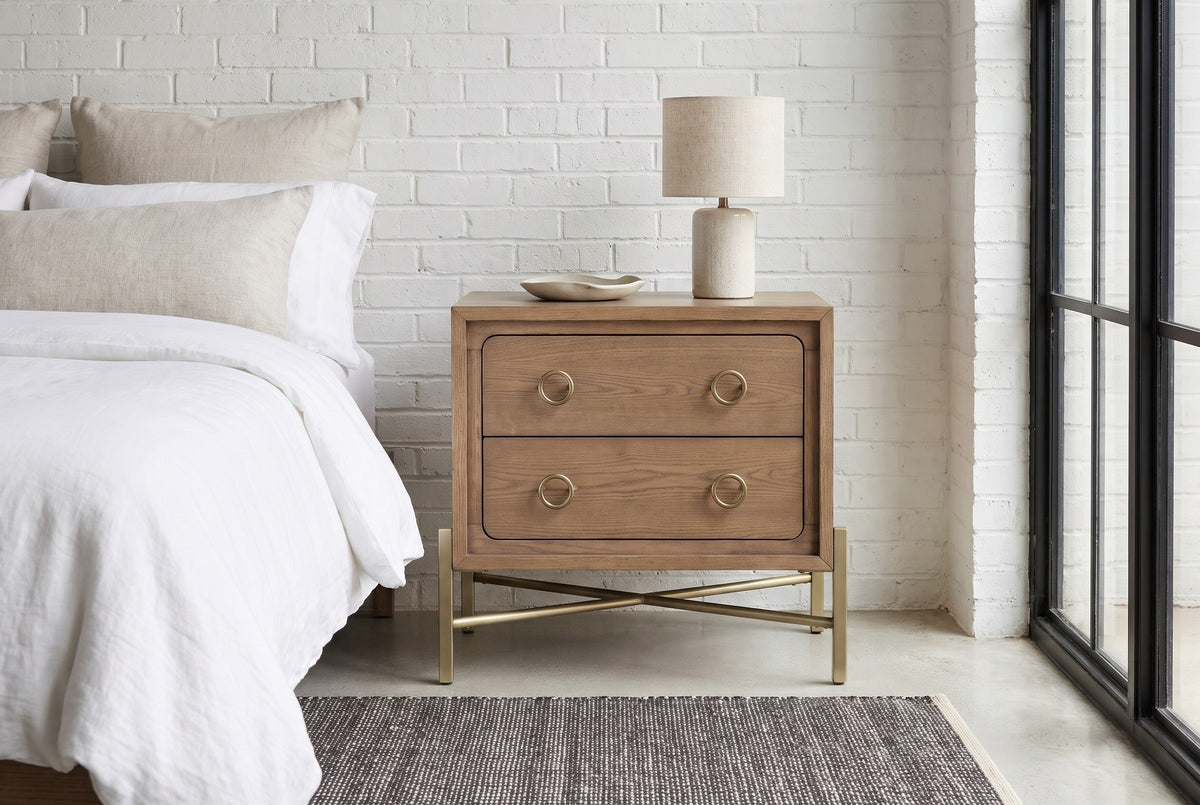 Cuglieri latte elm nightstand with a ceramic lamp against a white-painted brick wall in an Austin loft bedroom with a polished concrete floor and a black steel window
