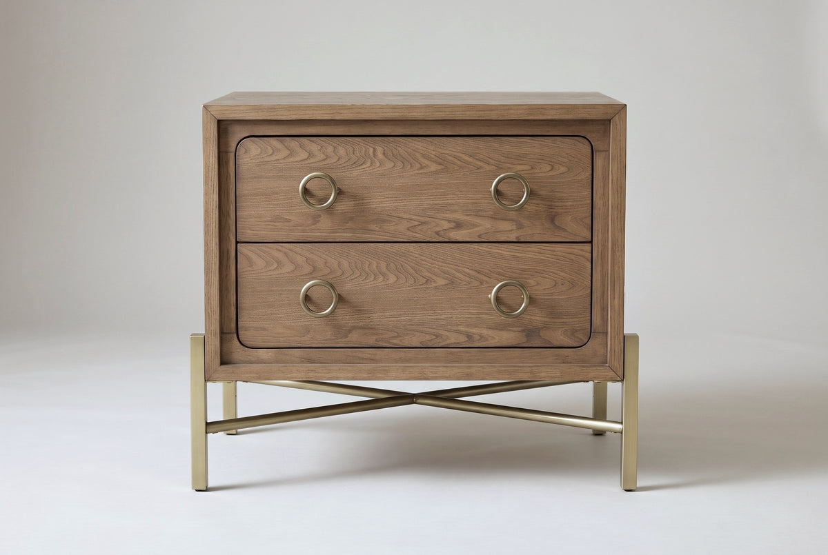 The Cuglieri nightstand in latte elm, front view on a light studio backdrop: two drawers with four brass ring pulls above a brass-tone stand with crossing rods