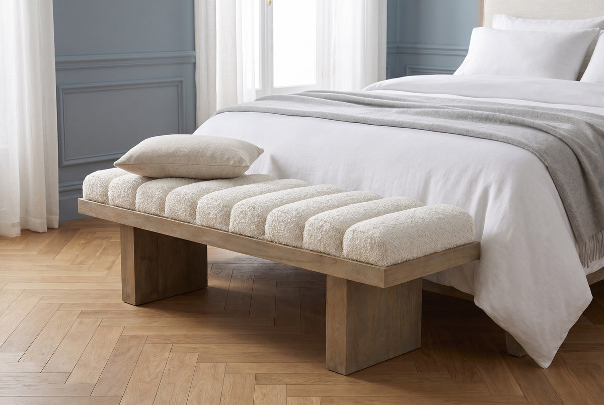 Deruta bench at the foot of a made bed in a Paris bedroom with dusty blue-grey panelled walls, white linen and a herringbone oak floor