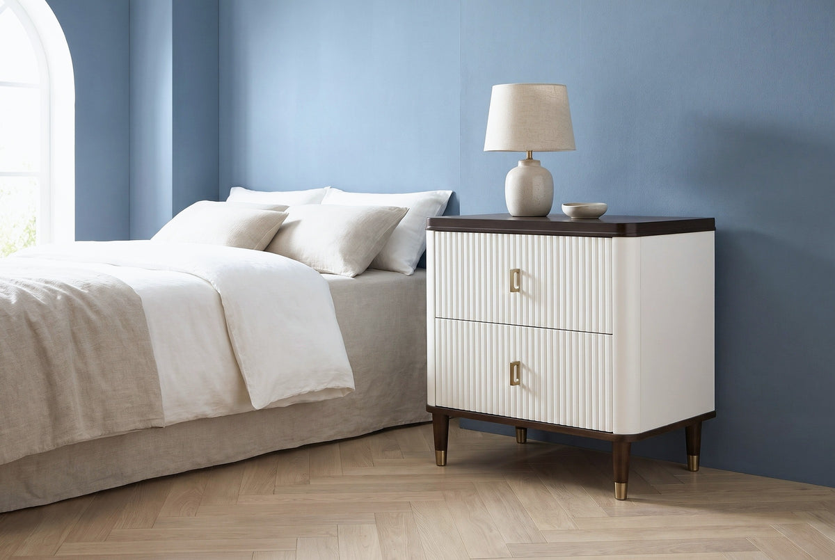 Desulo white fluted nightstand with a walnut-tone top and a ceramic lamp beside a bed in a Dallas bedroom with a dusty blue wall and an arched window