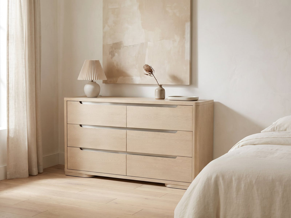 Este 66-Inch Light Elm 6-Drawer Dresser against a plaster wall under an abstract canvas in a bright bedroom