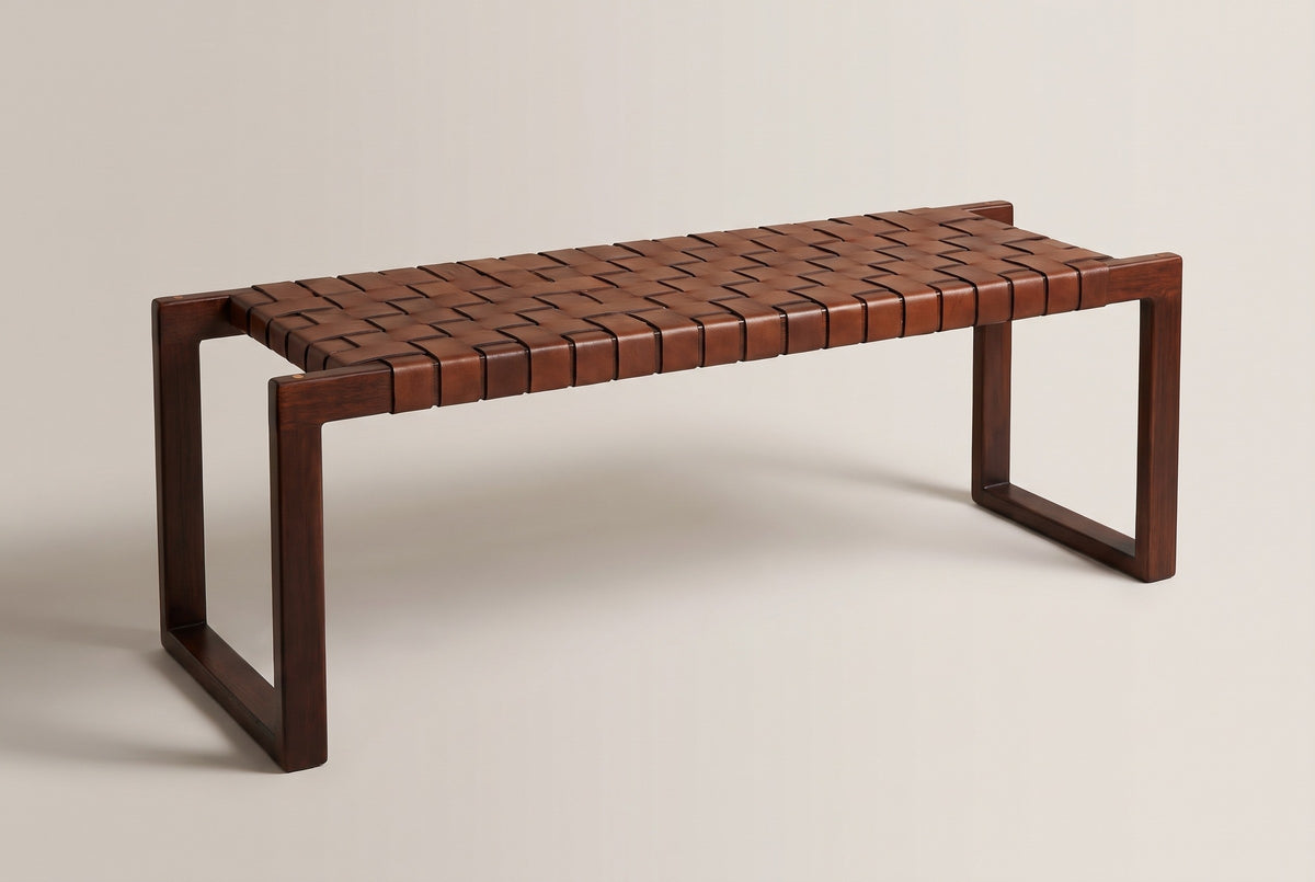 The Fasano bench with a woven cognac leather seat on two dark wood end frames, three-quarter view on a light studio backdrop