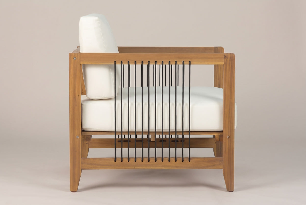 A Ficarra armchair seen from the side: the flat arm rail, the low side rail and the row of black cords between them, the ivory cushions behind