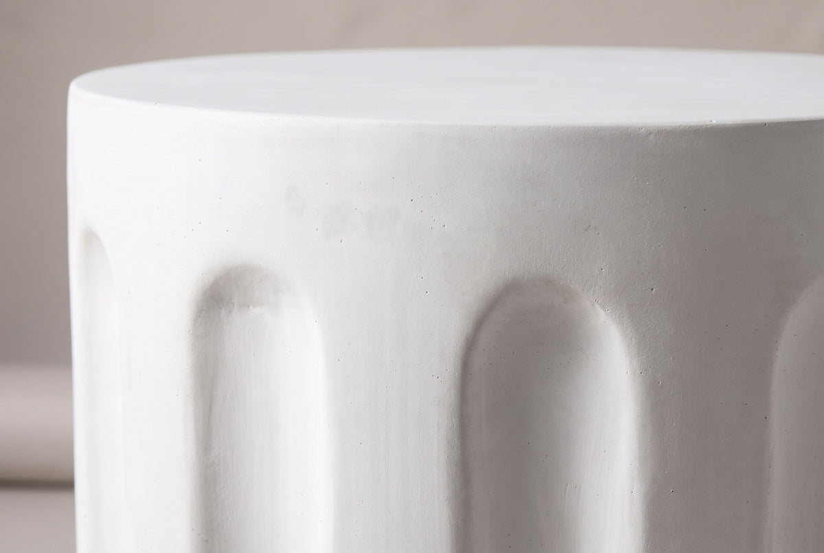 Close-up of the smooth white concrete at the top edge of the Ficuzza side table, with the arched tops of two flutes