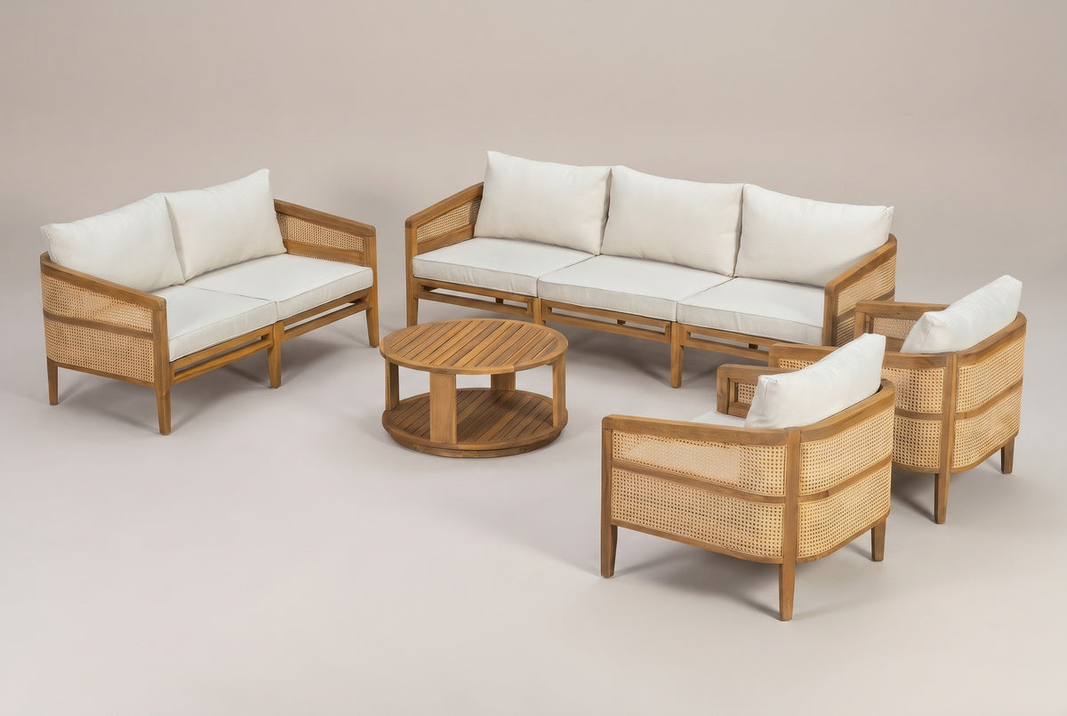 The Filicudi five-piece outdoor set: three-seat sofa, loveseat, two club armchairs and a round coffee table with ivory cushions, three-quarter view on a light studio backdrop