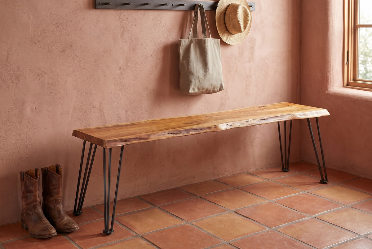 Foligno live-edge bench against a terracotta-pink lime-plaster wall in a Santa Fe entry hall with a saltillo tile floor, a coat rail with a tote and a straw hat, and leather boots beside it