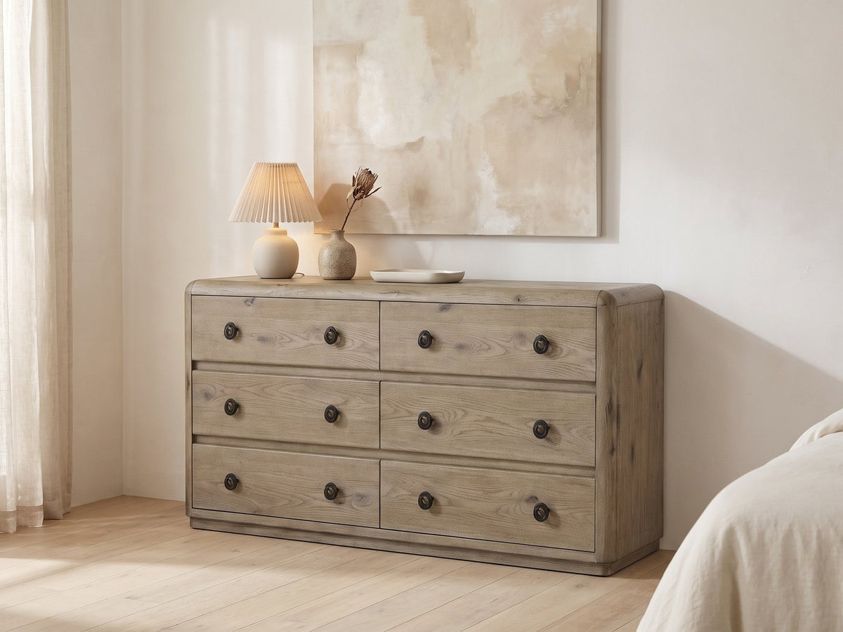 Fonzaso 66-Inch Weathered Knotty Oak 6-Drawer Dresser against a plaster wall under an abstract canvas in a bright bedroom