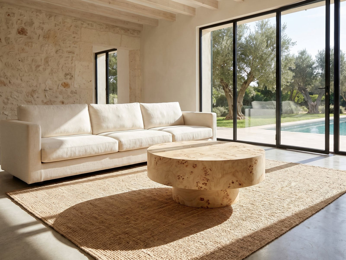 Fossano 31.5-Inch Round Burl Wood Veneer Pedestal Coffee Table on a jute rug in front of a linen sofa in a poolside villa