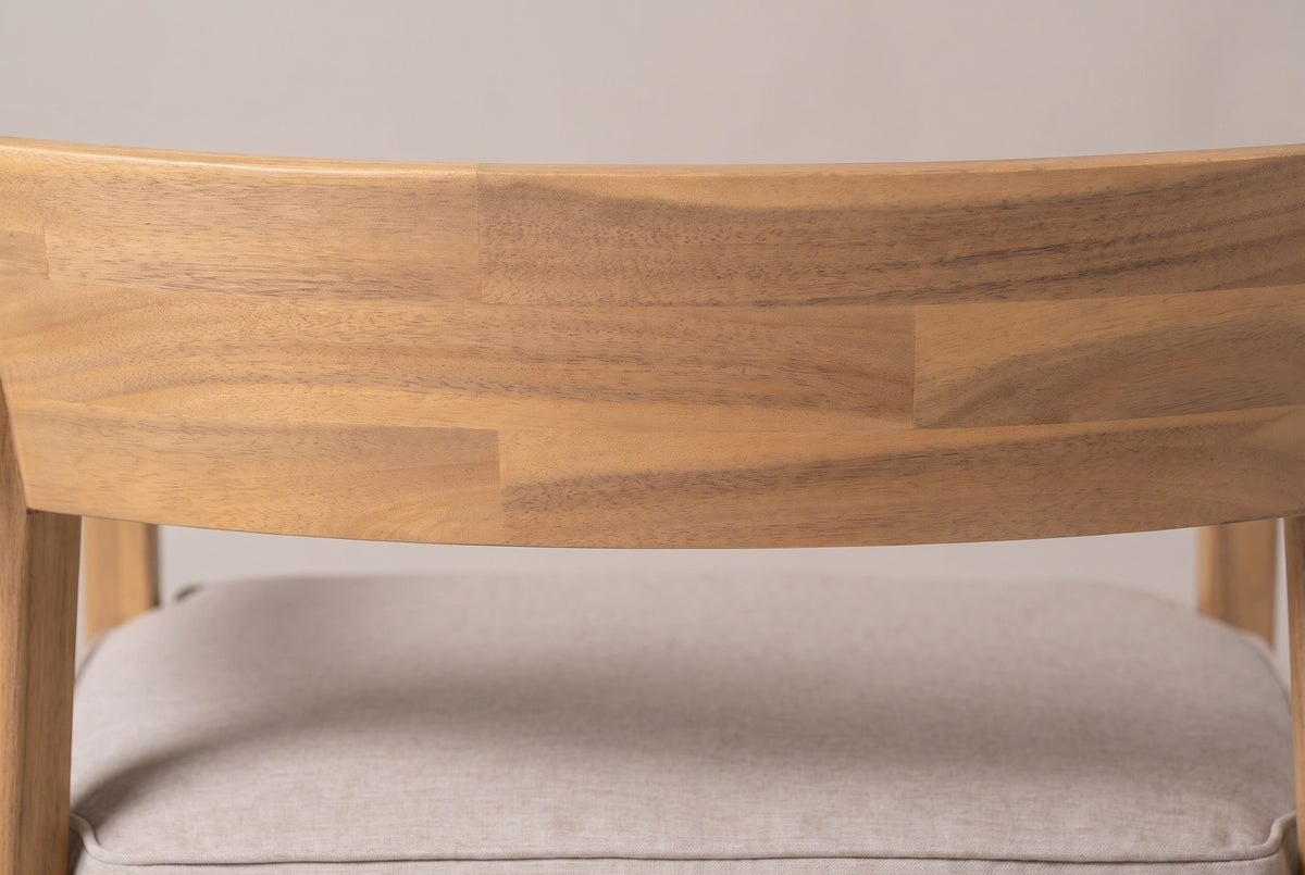 Close-up of the curved acacia back panel on the Furnari club chair, joined strips in pale honey tones above the beige seat cushion