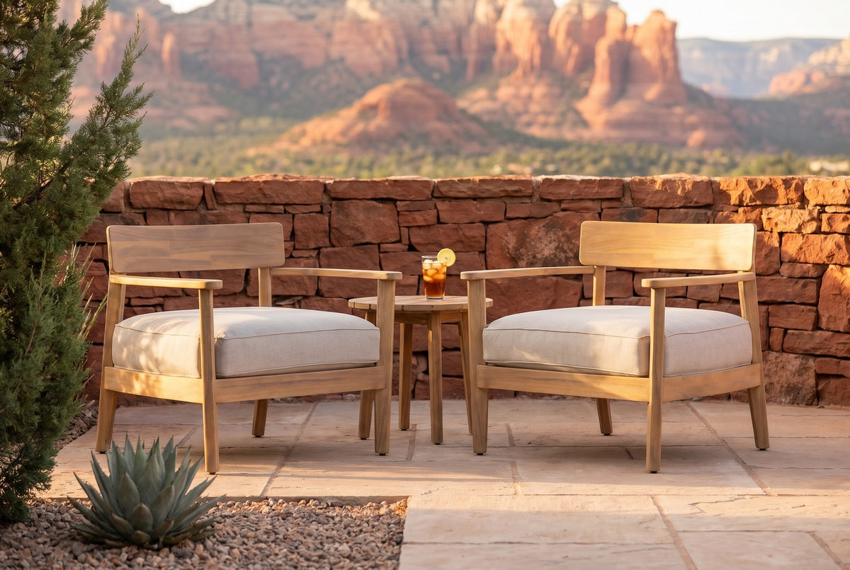 Two Furnari acacia club chairs on a flagstone patio in Sedona at golden hour, a red sandstone wall and red rock buttes behind (side table not included)