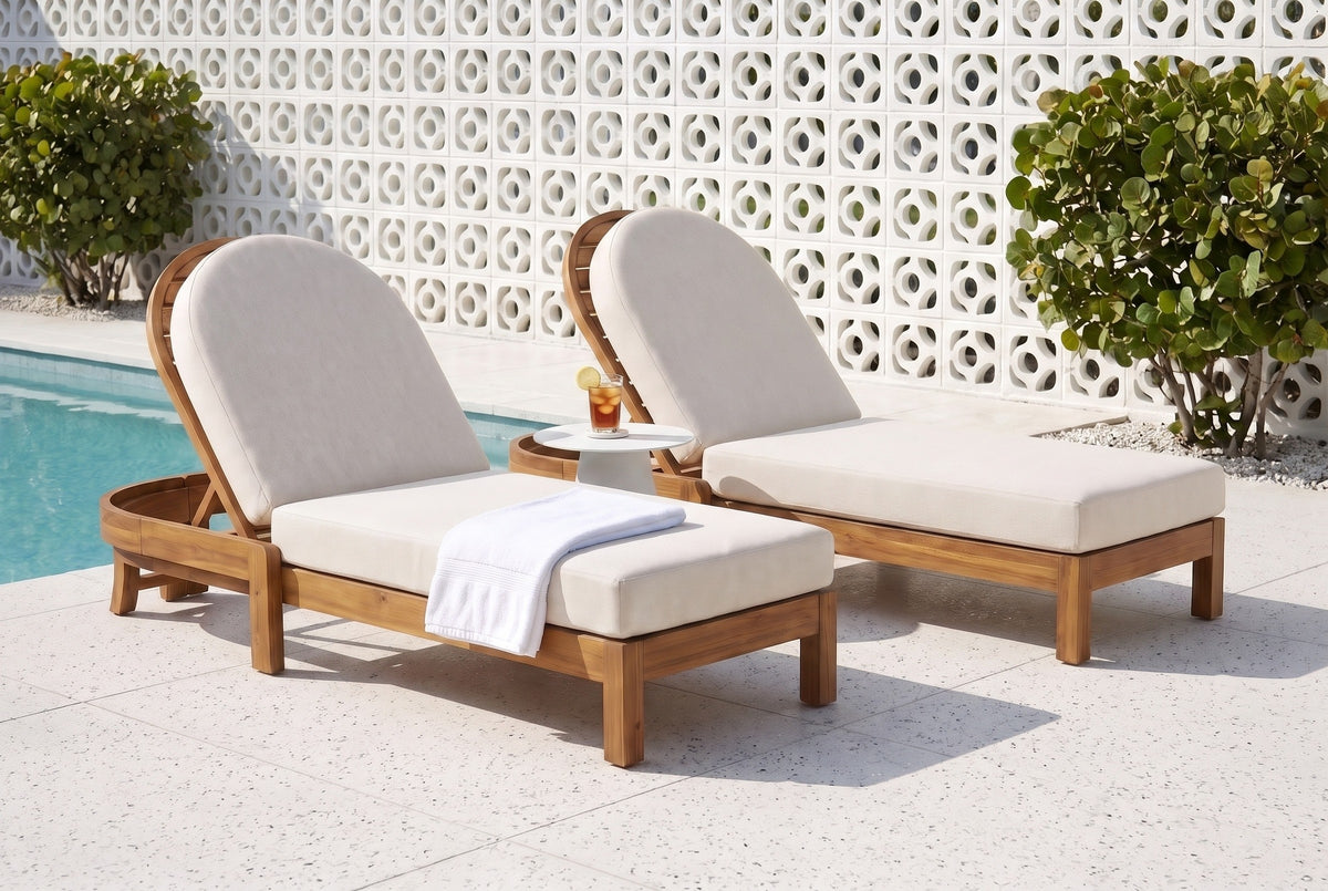 Two Gangi acacia chaise lounges with beige cushions on a terrazzo pool deck in Sarasota, a white breeze-block screen wall and sea grape behind (side table and towel not included)