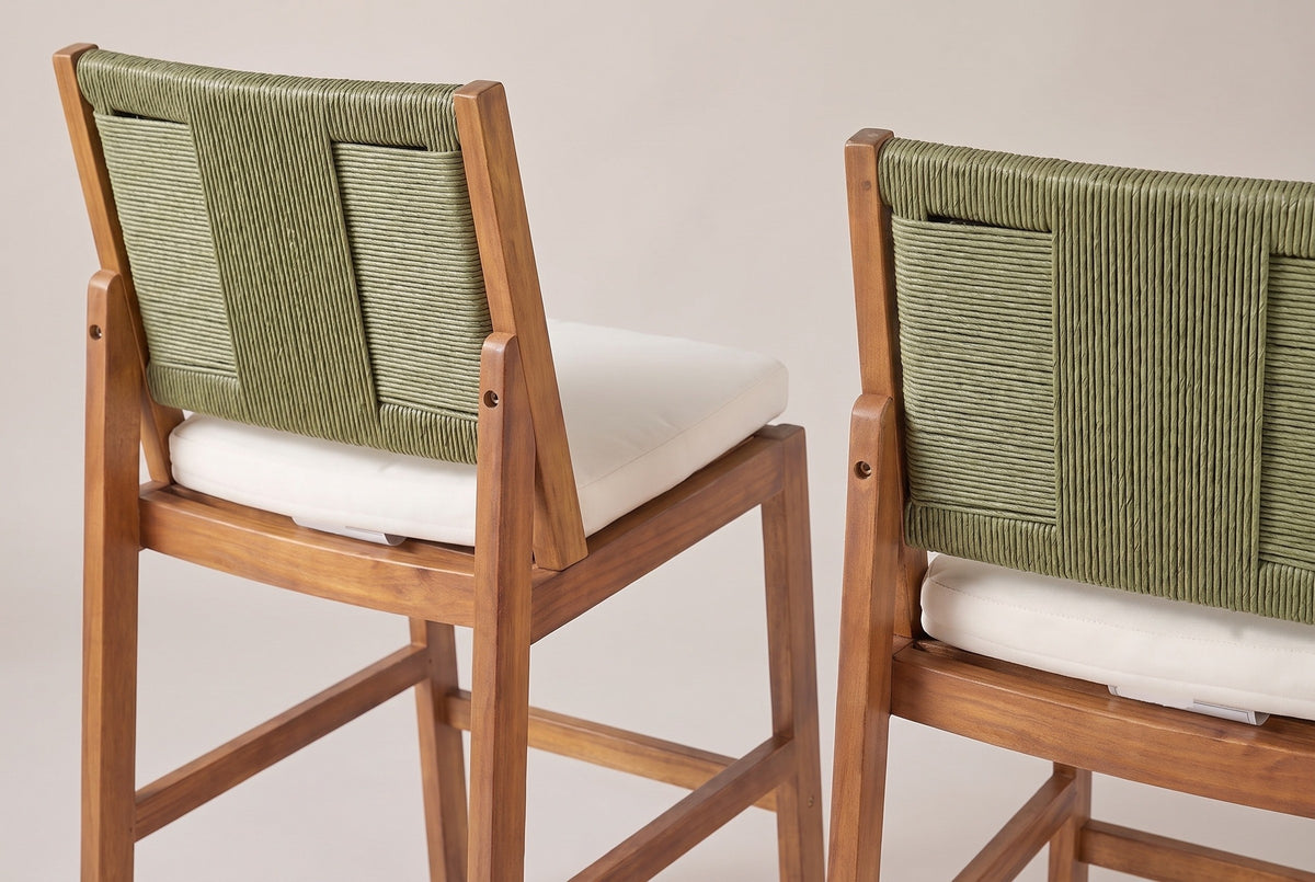 The Ganzirri stools from behind: the sage-green woven backs, the leaning back posts bolted to the rear legs and the ivory cushions