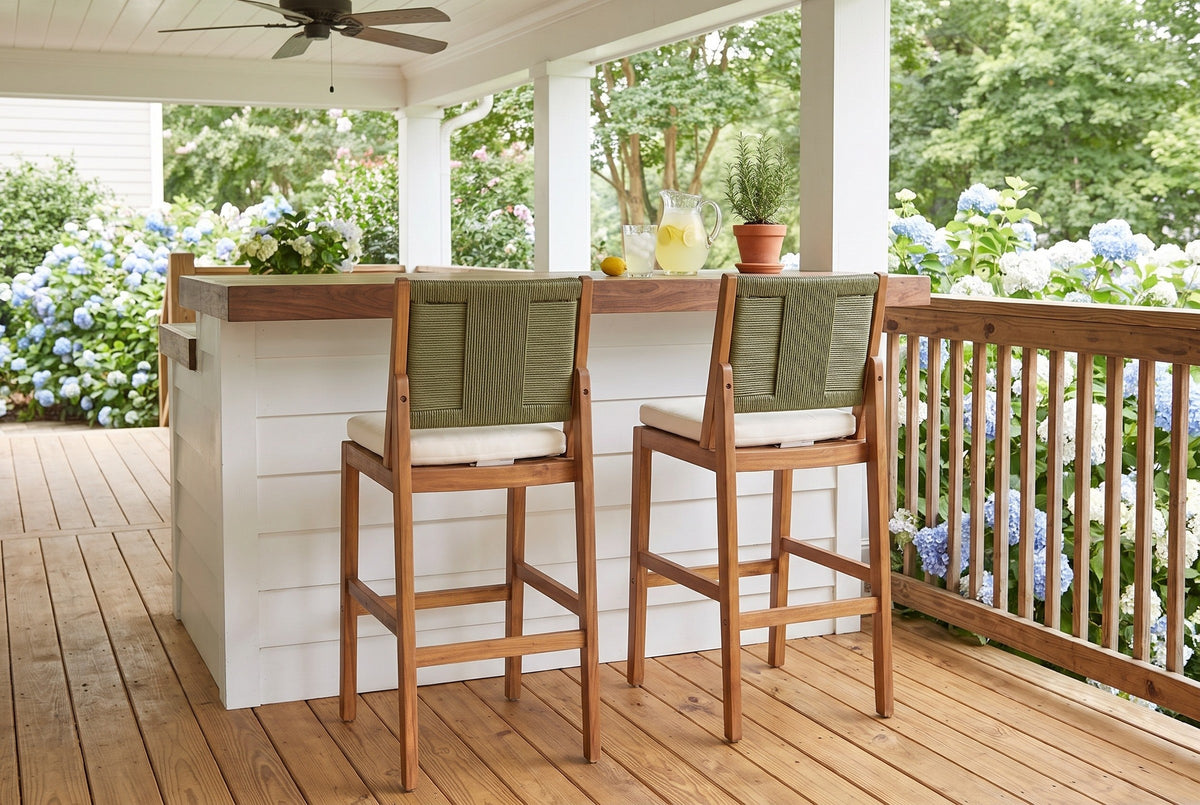 Two Ganzirri acacia bar stools at a walnut-topped shiplap bar on a covered farmhouse porch near Athens, Georgia, with blue hydrangeas beyond the rail (bar counter not included)