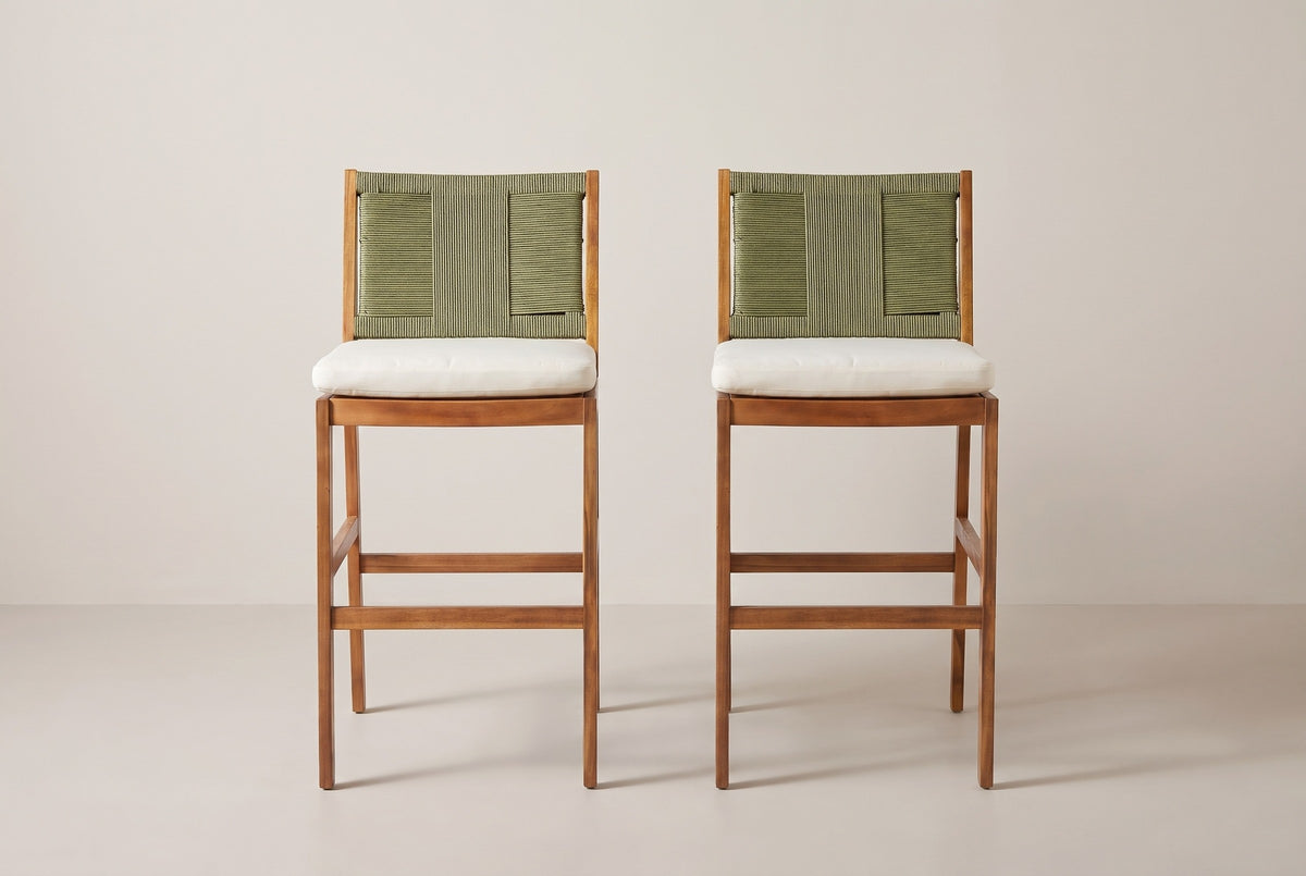 The two Ganzirri bar stools seen straight from the front: woven backs, ivory cushions, square legs and the low footrest rails