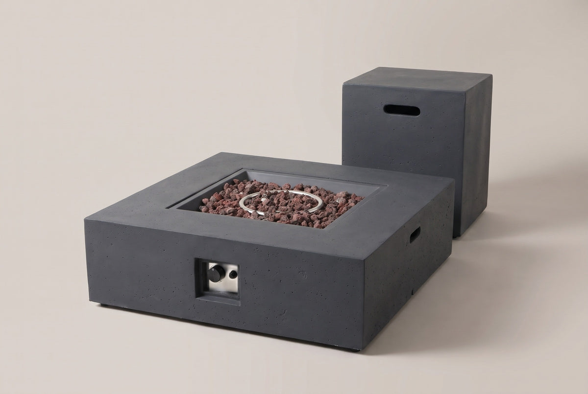 The Gela square fire pit and its tank holder in dark gray concrete, three-quarter view on a light studio backdrop, the control niche on the front face