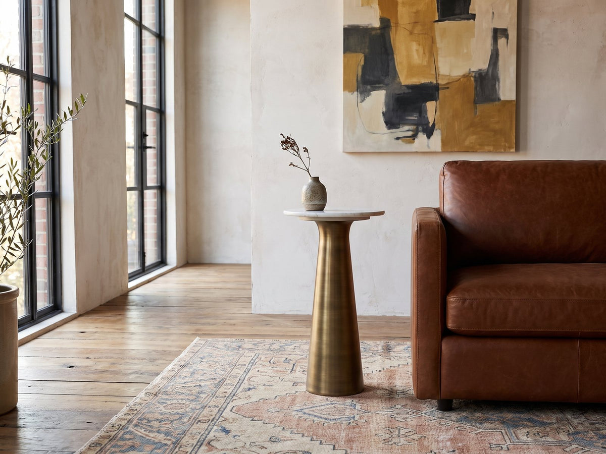 Genazzano White Marble Tapered Pedestal Side Table with a stoneware vase beside a cognac leather armchair in a sunlit loft