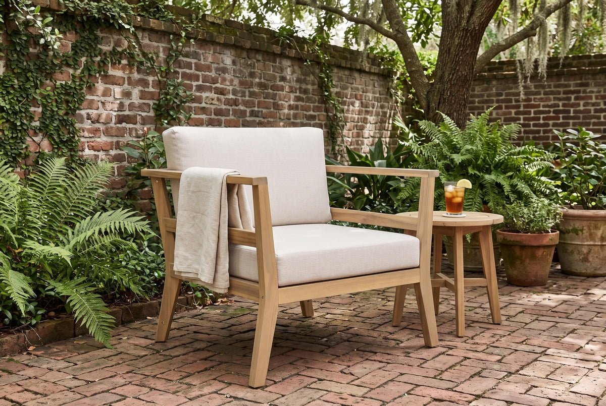Geraci acacia club chair in a Savannah walled garden with an old brick wall, ferns and a herringbone brick floor (side table and throw not included)