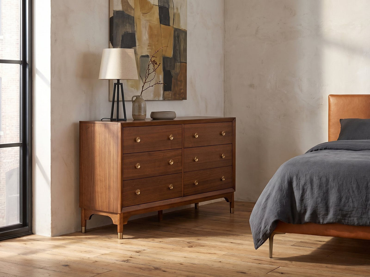 Gorizia 62-Inch Warm Walnut 6-Drawer Dresser against a plaster wall in an industrial loft bedroom