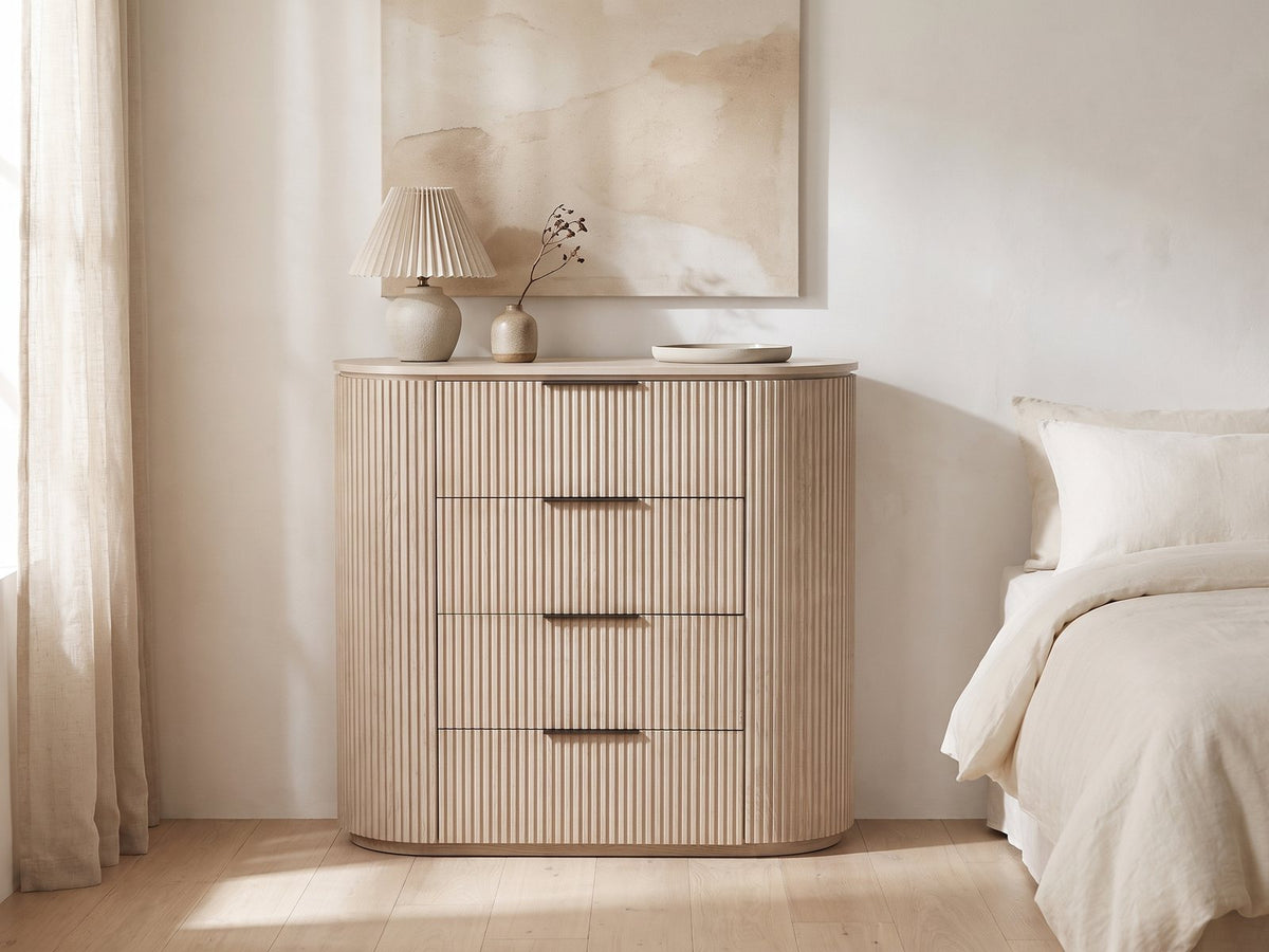 Gradisca 50-Inch Light Oak 4-Drawer Chest against a plaster wall under an abstract canvas in a bright bedroom