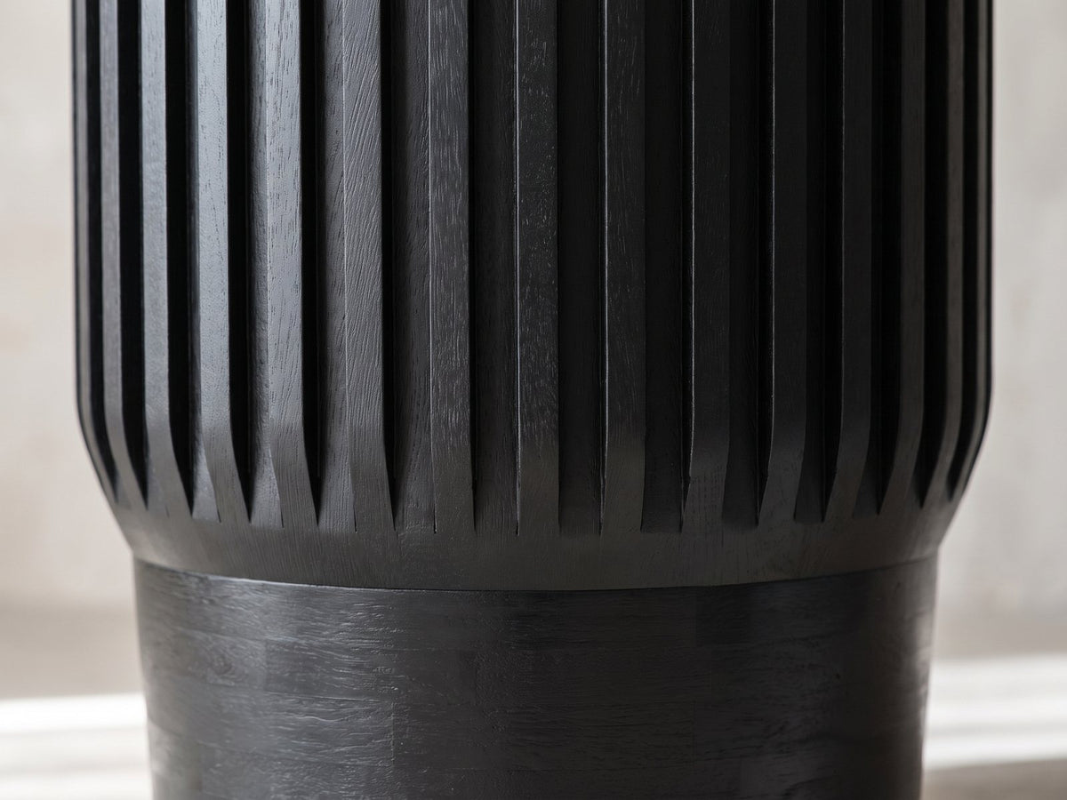 Close-up of the Grottole Black Mango Ribbed Drum Side Table: the black ribs tapering to points above the stacked mango base