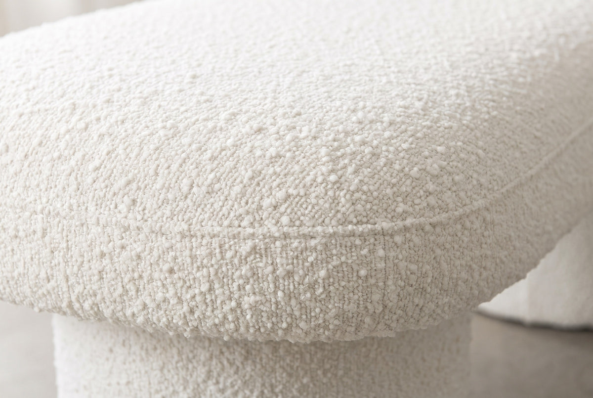 Close-up of the ivory boucle on the Gubbio bench: loops and small nubs in a soft warm white, with a fine seam along the rounded edge of the top