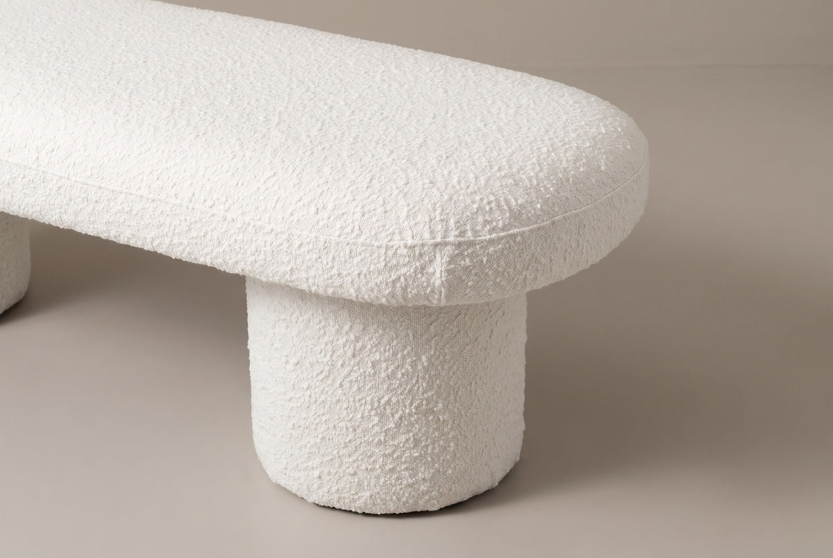 One end of the Gubbio bench: the rounded end of the thick boucle top with its fine seam, overhanging the drum leg below