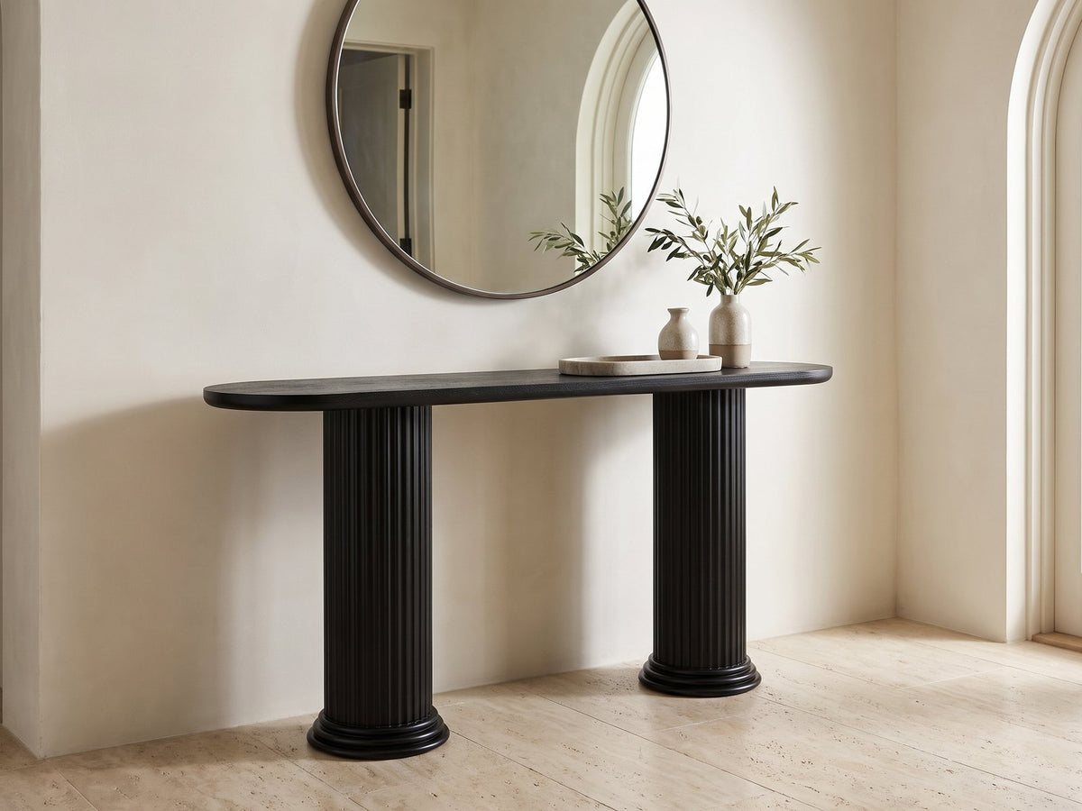 Imola Black Wood Veneer Oval Column Console Table under a round mirror in a travertine entryway
