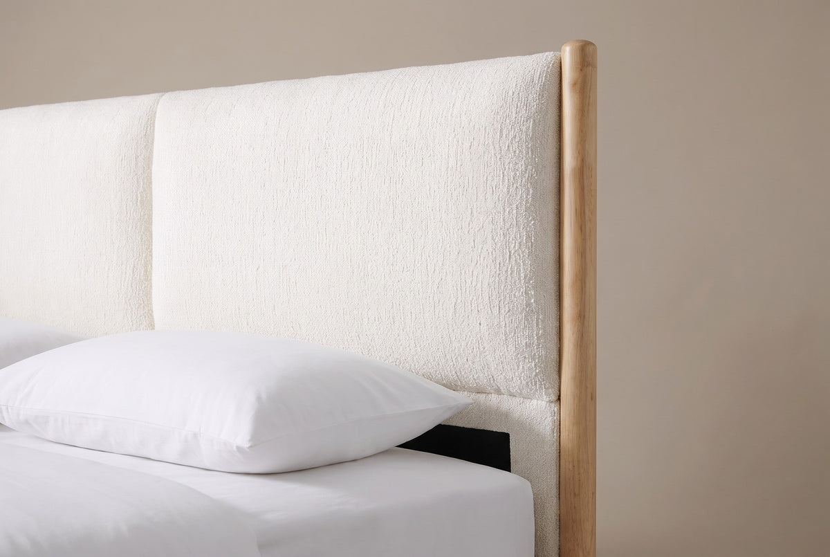 One side of the Isernia headboard: a round wooden post with a domed top, a plump cream cushion with a rounded corner and the seam to the second cushion, above a white pillow