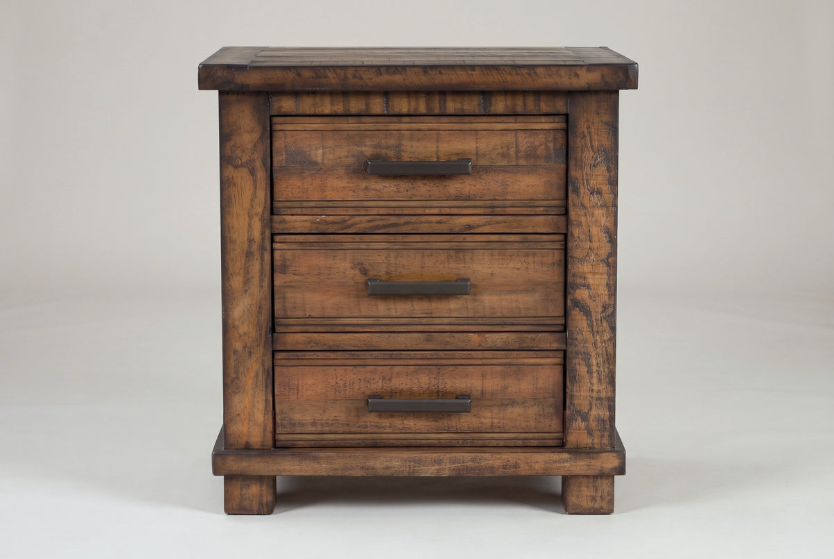 The Ittiri three-drawer nightstand in reclaimed pine, front view on a light studio backdrop: a framed plank top, three drawers with bronze bar pulls, wide corner posts, a base rail and block feet