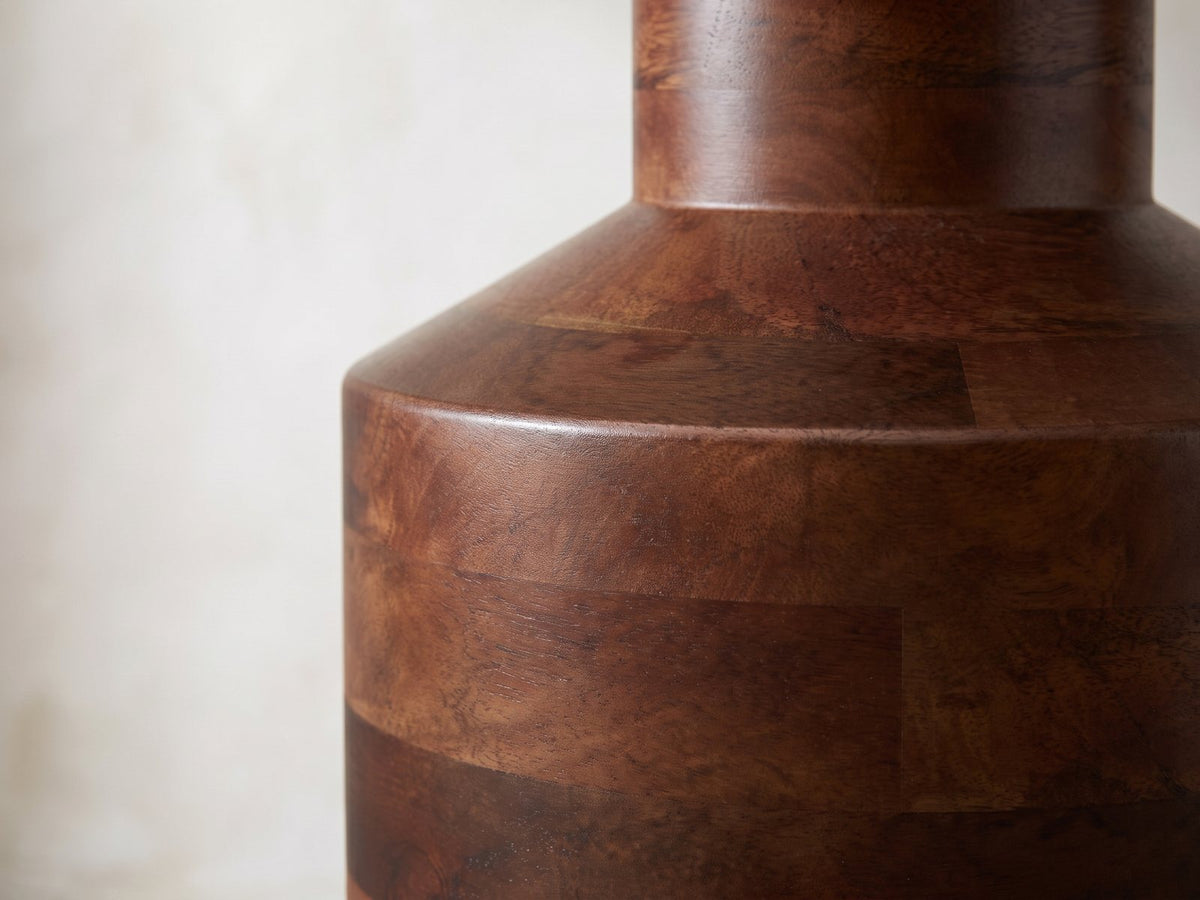 Close-up of the Lagonegro Solid Mango Pedestal Side Table: the neck and sloping shoulder over the stacked mango blocks