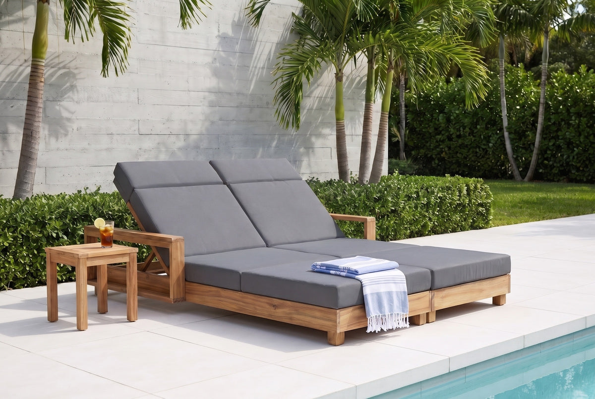 Lampedusa double chaise lounge with dark grey cushions on a Miami Beach pool terrace with a board-marked concrete wall, palms and a turquoise pool (side table and towel not included)