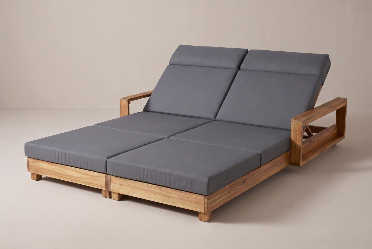 The Lampedusa double chaise lounge in light natural acacia with two dark grey four-fold cushions, both backrests raised, three-quarter view on a light studio backdrop