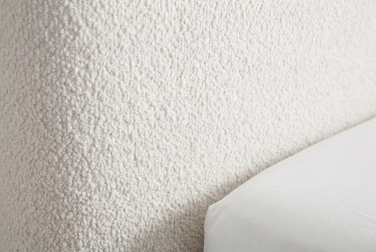 Close-up of the Lanciano pearl white chenille upholstery, a dense nubby curly weave, beside the edge of a white mattress cover