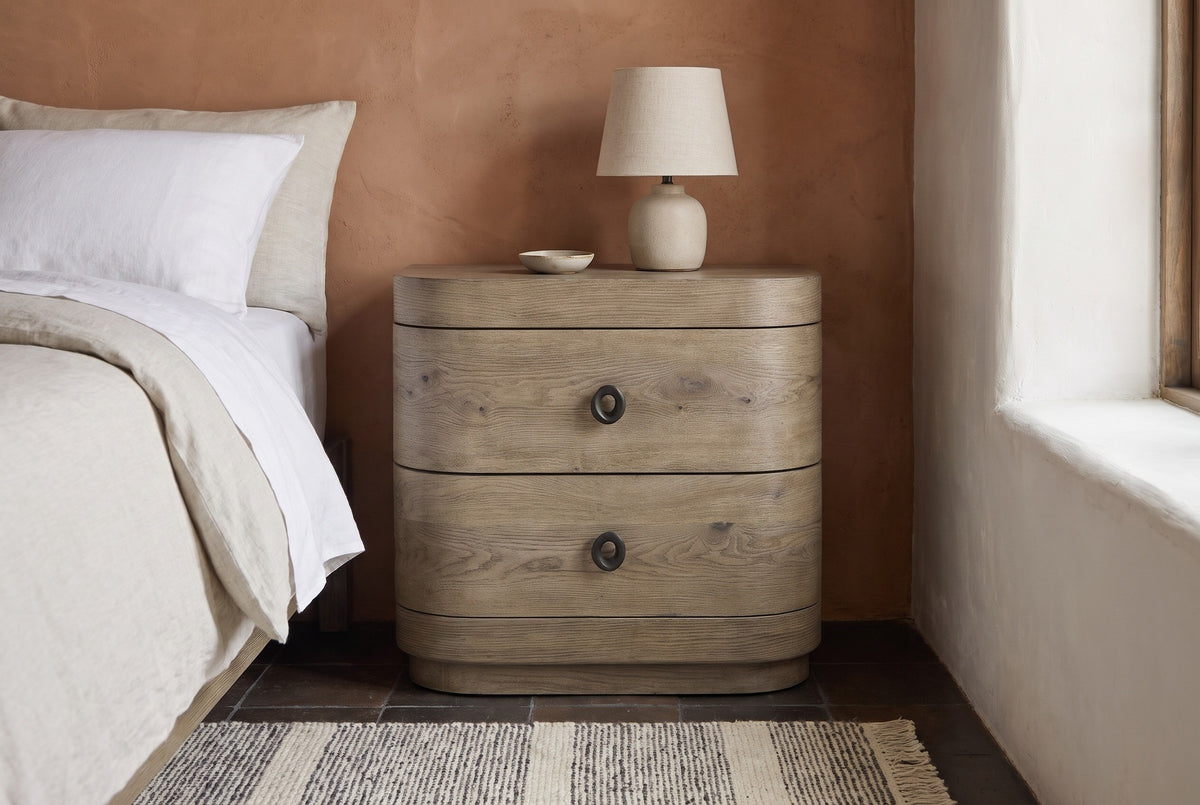Lanusei knotty oak nightstand against a terracotta plaster wall in a Santa Fe bedroom with a dark tile floor, a woven rug and a deep window