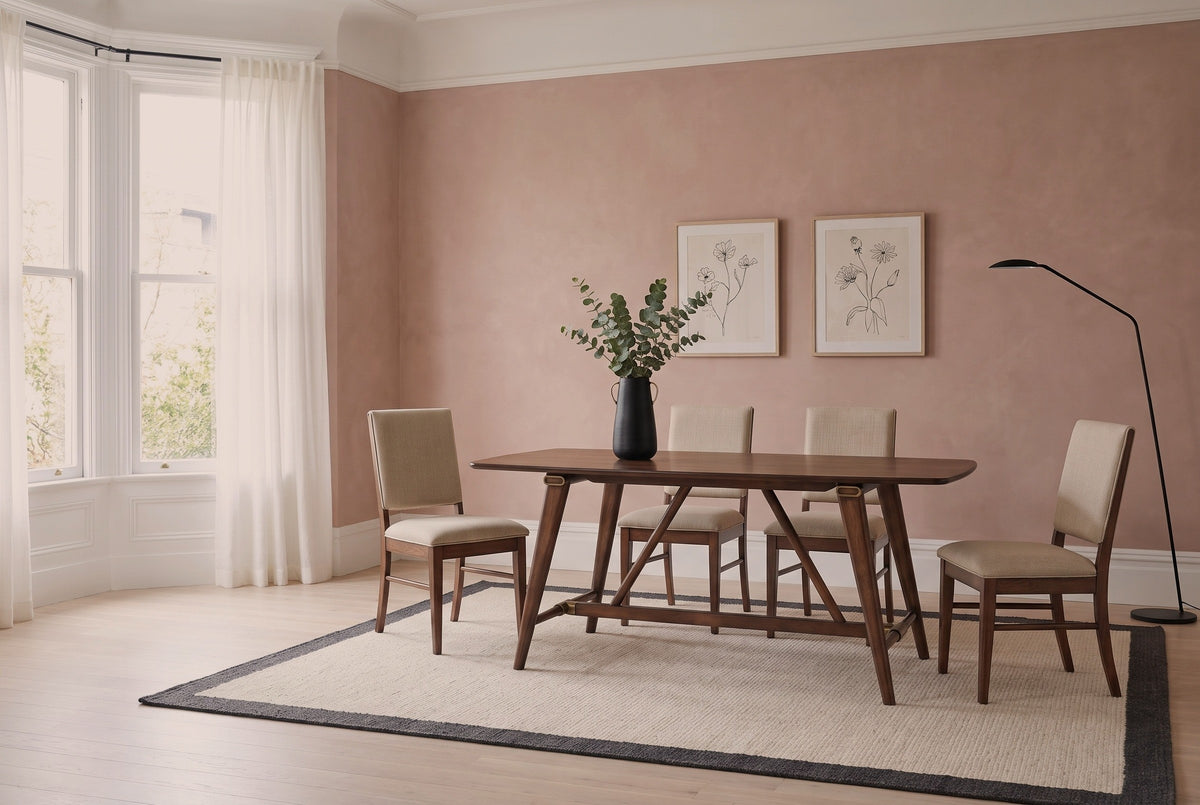 Lavello trestle dining table with four upholstered chairs on a pale rug in a San Francisco dining room with a clay-pink plaster wall and a bay window