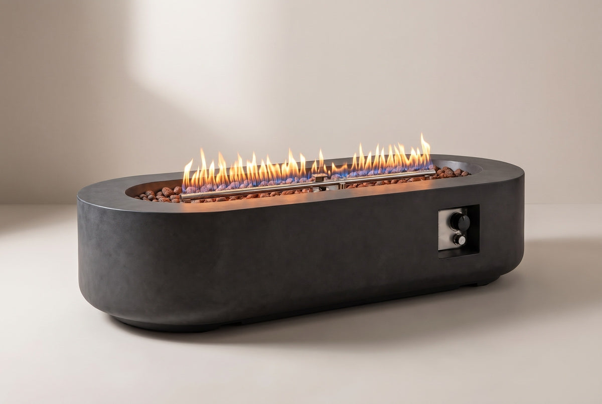 The Licata oval concrete fire pit table with a lit flame over volcanic rock, three-quarter view on a light studio backdrop