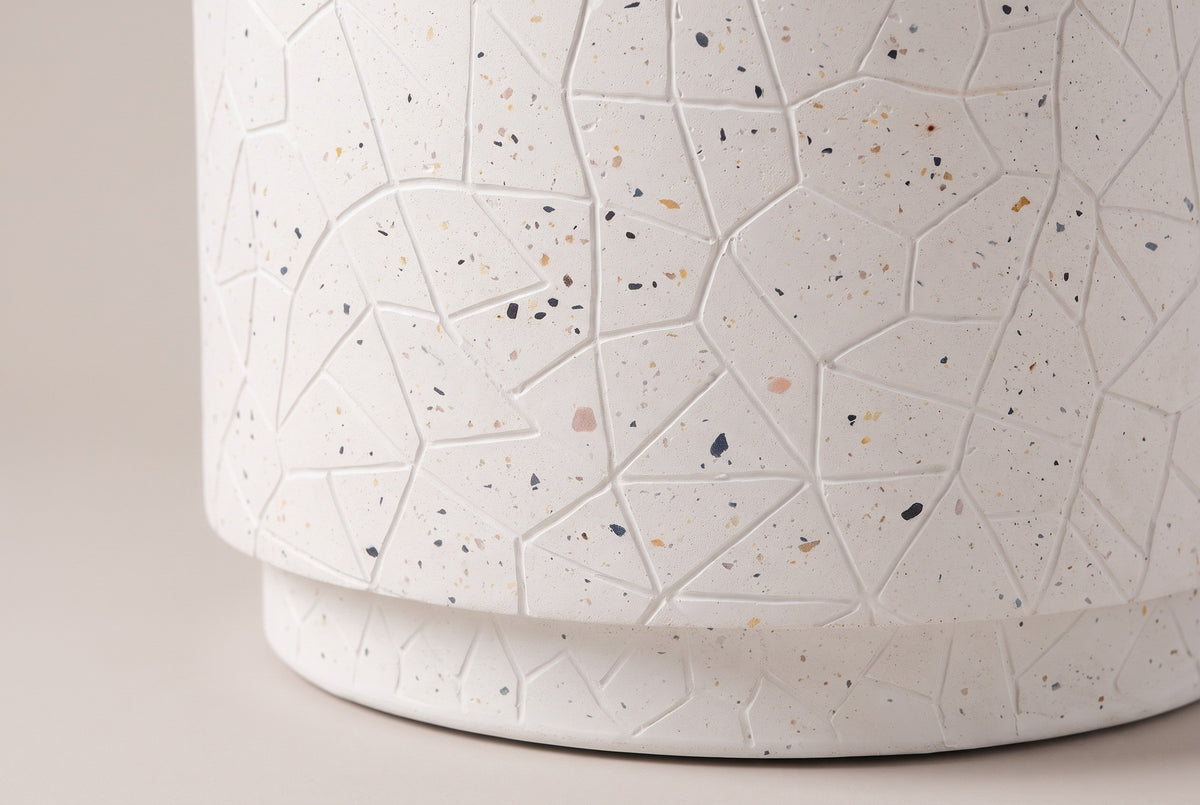 Close-up of the white concrete on the Linguaglossa side table: raised crackle lines, small multicolour flecks and the step down to the plinth
