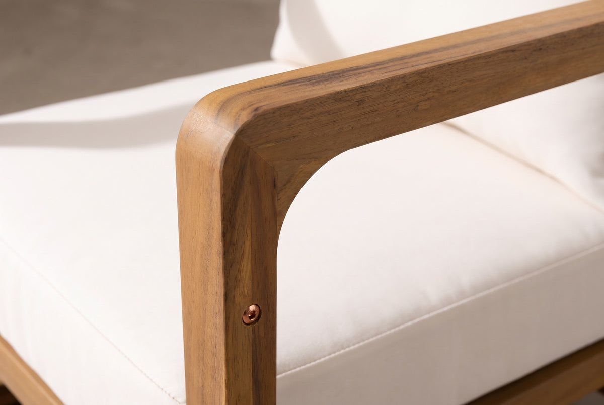 Close-up of the solid acacia on a Linosa chair: the rounded corner where the arm meets the front post, a copper-coloured bolt head and the white seat cushion