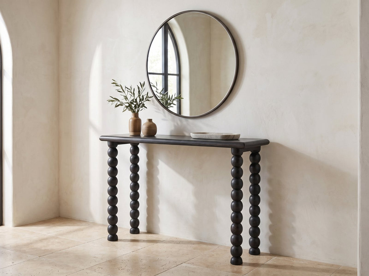 Lizzano Black Mango Wood Bobbin Console Table under a round mirror in a travertine entryway