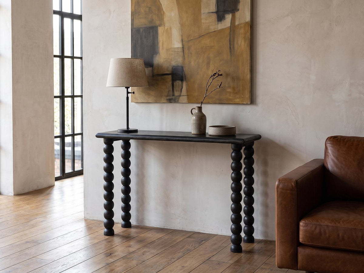 Lizzano Black Mango Wood Bobbin Console Table against a plaster wall in an industrial loft