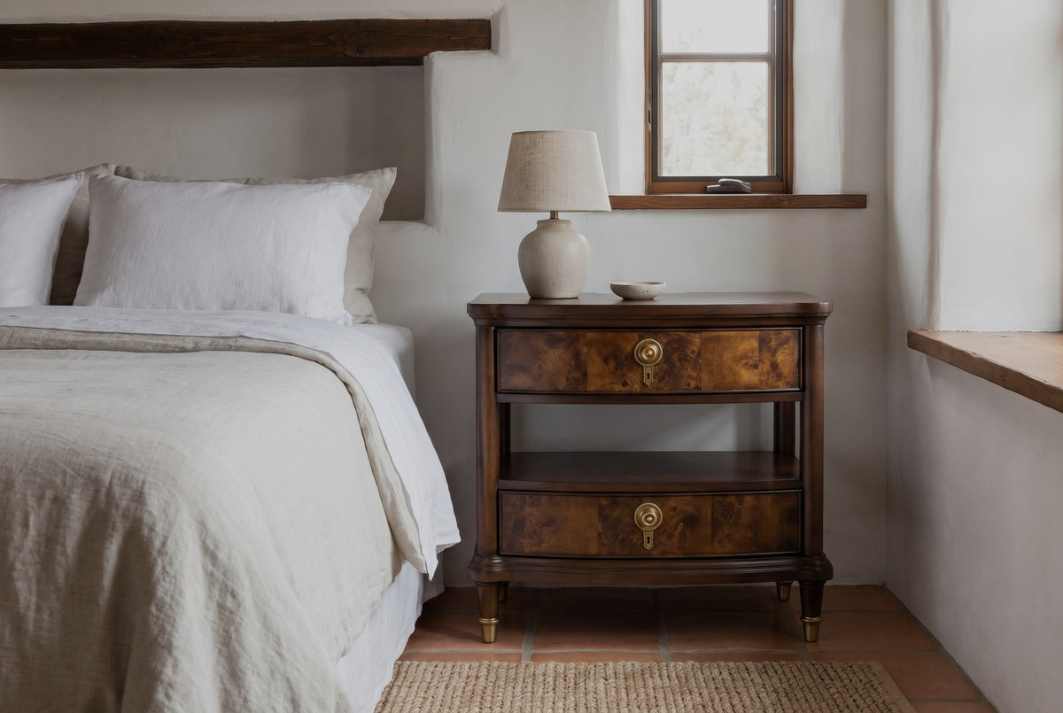 Luras dark cherry and burl nightstand with a ceramic lamp against a white limewashed plaster wall in a Santa Fe adobe bedroom with a terracotta tile floor and a woven rug