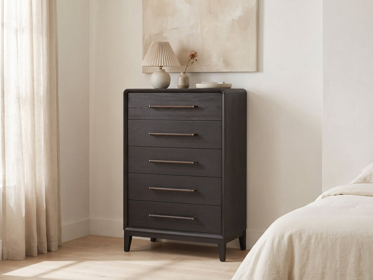 Lusiana 35-Inch Peppercorn Black 5-Drawer Chest against a plaster wall under an abstract canvas in a bright bedroom